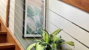 A staircase with wooden steps and a potted plant with broad leaves. - This architect-designed Straddie beauty is the perfect laid-back beach house (Point Lookout)