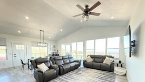 A spacious living room with a large sectional sofa, a dining area, and a ceiling fan.