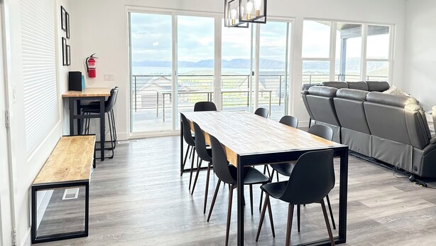 A modern interior with a dining area, a sofa, and a view of the outdoors.