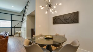 A dining area with a round table, six chairs, a chandelier, and a large abstract painting on the wall. - Upscale Texarkana Townhome, Walk to Downtown! (Texarkana)
