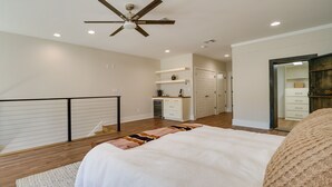 A bedroom with a bed, a ceiling fan, a kitchen area, and a bathroom. - Upscale Texarkana Townhome, Walk to Downtown! (Texarkana)