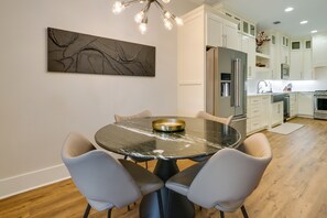 A modern kitchen with white cabinetry, a marble dining table, and a contemporary light fixture. - Upscale Texarkana Townhome, Walk to Downtown! (Texarkana)