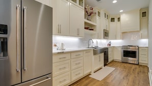 A modern kitchen with stainless steel appliances, white cabinetry, and wooden flooring. - Upscale Texarkana Townhome, Walk to Downtown! (Texarkana)