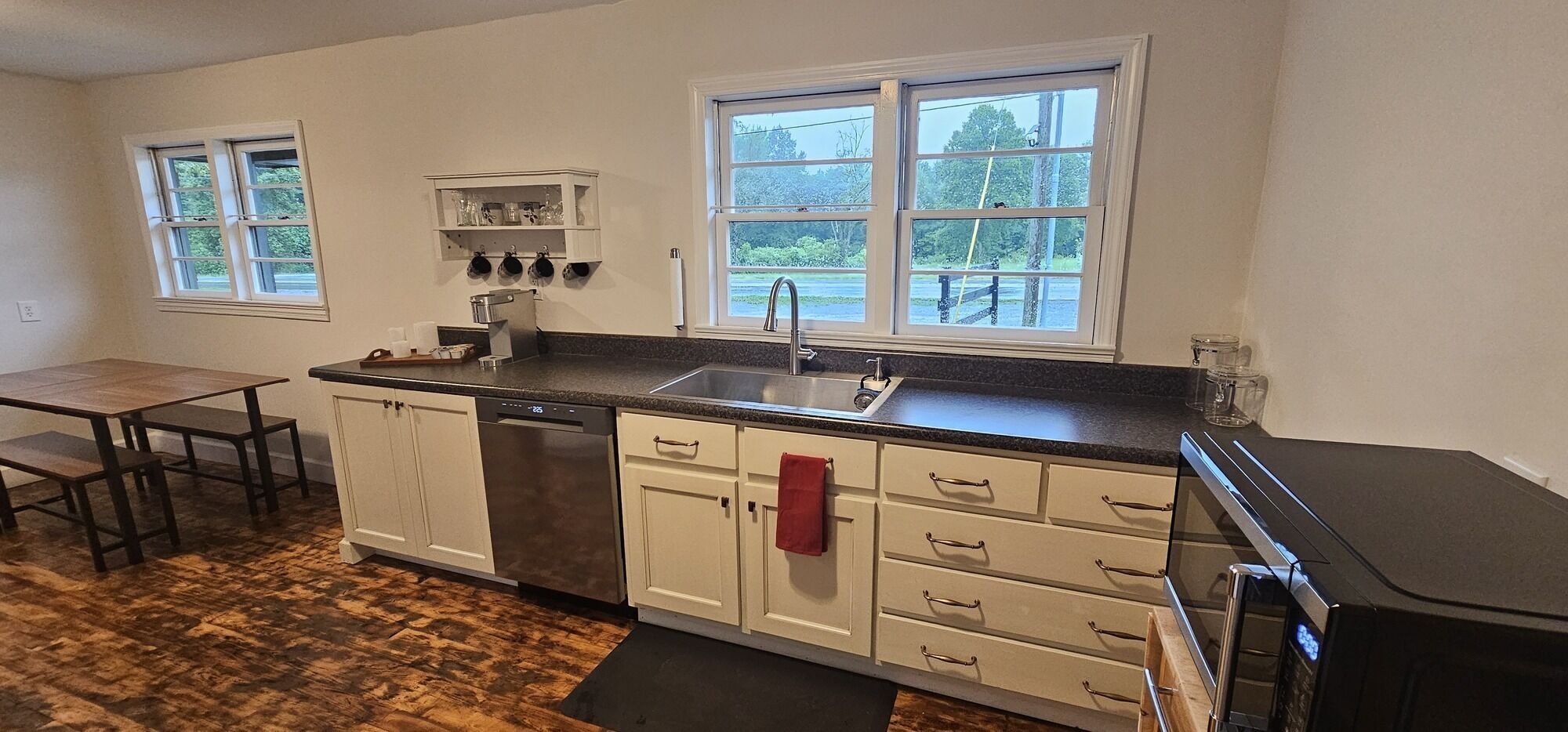 A kitchen with a dishwasher, sink, and a window overlooking a parking lot.