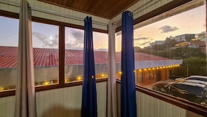 A room with a view of a building with a red roof and a car parked outside. - Cabinas Selva Verde (Monteverde)