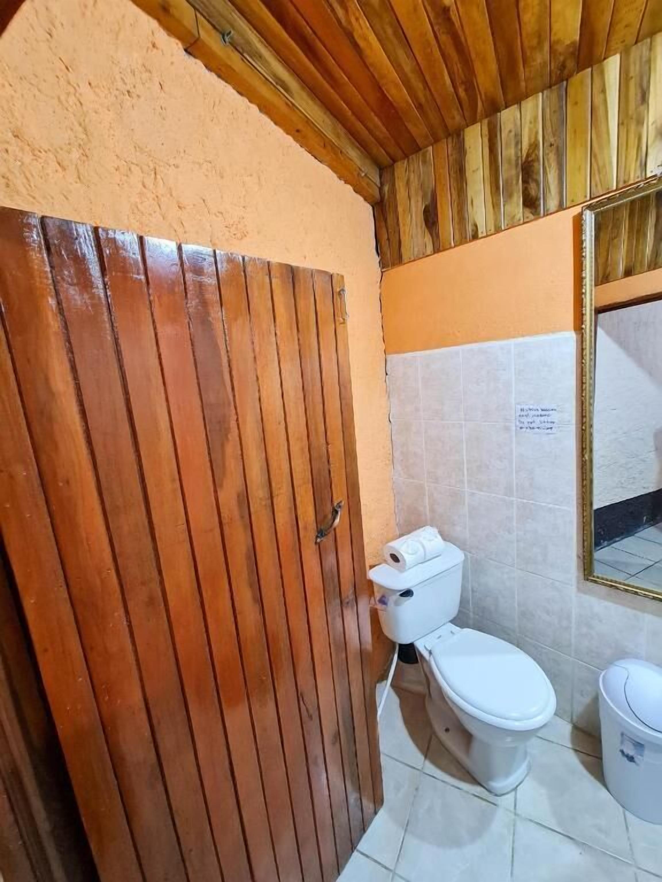 Een badkamer met een houten deur, toilet en een bidet.
