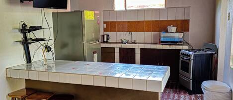 Una cocina compacta con techo de madera, salpicadero de azulejos, cocina integrada y un ventanal pequeño.