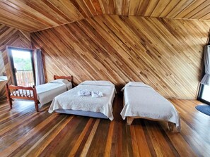 A room with two beds, wooden flooring, and a sloped ceiling. - Cabinas Selva Verde (Monteverde)