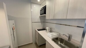 A compact kitchen with a stainless steel sink, a white refrigerator, and a microwave on a white countertop. - San Telmo Beautiful Studio (Buenos Aires)