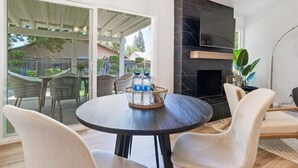 A modern living room with a round table, two chairs, a fireplace, and a view of the outdoors.