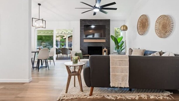 A modern living room with a dark sofa, a small round table, and a ceiling fan.