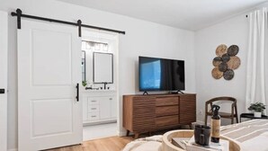 A bedroom with a bed, a TV, a wooden dresser, and a door.