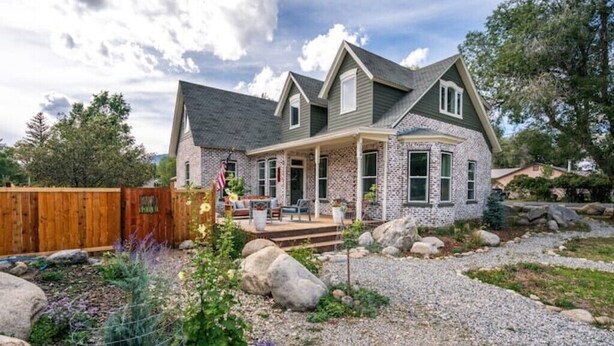 A two-story house with a stone facade, a covered porch, and a landscaped garden with rocks and plants. - The Isabella House: Historical, Beautifully Renovated, Walkable to Main Street

 (Buena Vista)