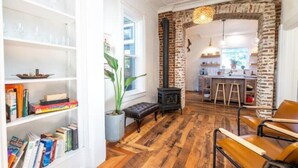 A cozy living room with a fireplace, wooden flooring, and a bookshelf filled with books. - The Isabella House: Historical, Beautifully Renovated, Walkable to Main Street

 (Buena Vista)