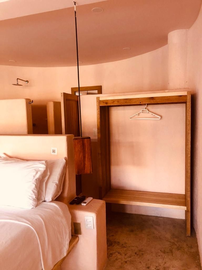 Ein Schlafzimmer mit einem Bett, einer Holzhängeregals und einer Pendelleuchte.