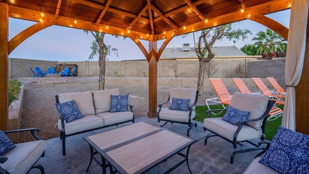 Eine Außenpatio mit einer Holzpergola, gepolsterten Sitzgelegenheiten und einem Poolbereich.