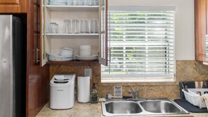 A kitchen with wooden cabinets, a built-in wine rack, a double sink, and a window with blinds.