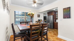 A modern kitchen with a stainless steel refrigerator, wooden cabinets, and a dining area with a table and chairs.