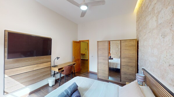 Un dormitorio moderno con cama, mesita de noche, lámpara y un espejo grande.