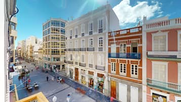 A street view of a city with historic buildings, a modern glass structure, and a clear blue sky.