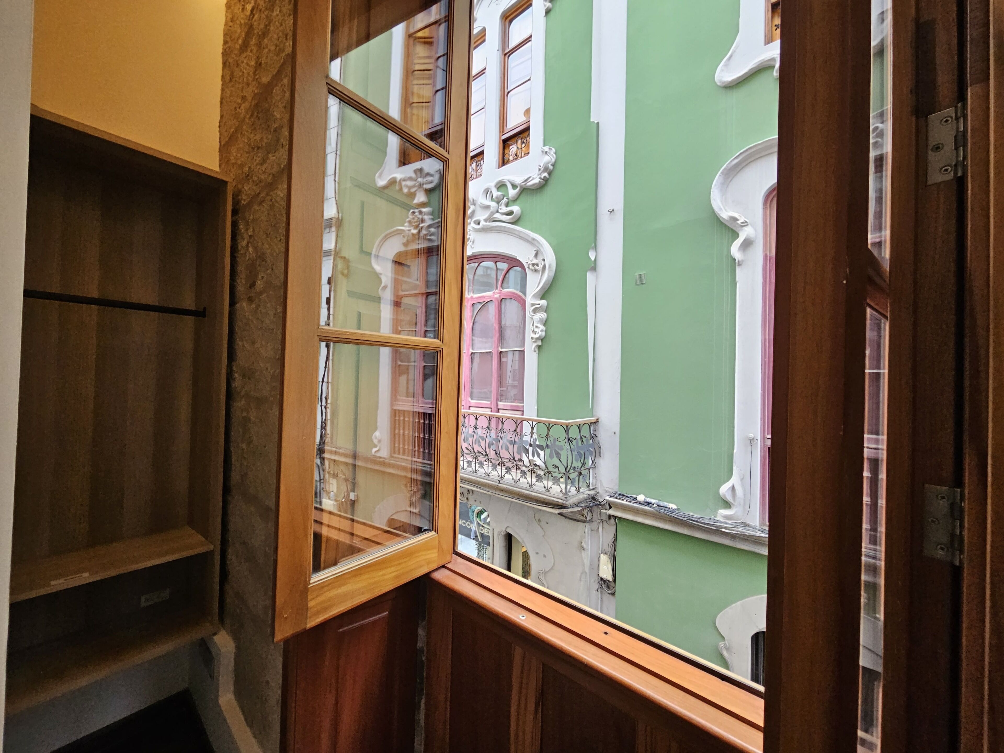 A corner of a room with a wooden cabinet and a window with ornate white trim.
