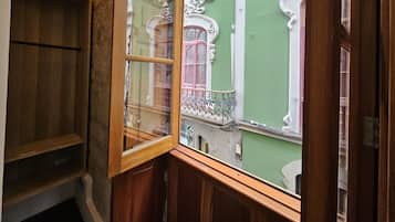 A corner of a room with a wooden cabinet and a window with ornate white trim.
