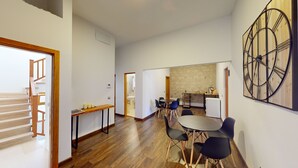 A spacious living area with a dining table, chairs, and a kitchen in the background.