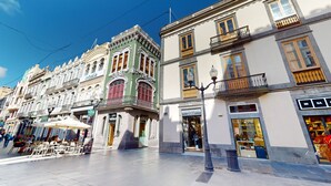 A street with historic buildings, outdoor seating, and a clear sky.