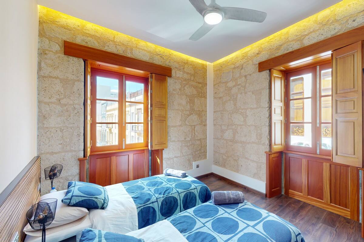 A bedroom with two beds, wooden doors, and a ceiling fan.