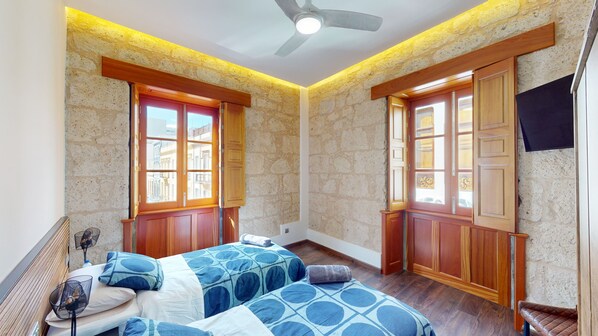 Un dormitorio con dos camas, puertas de madera y un ventilador de techo.