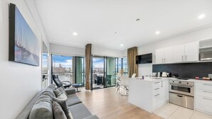 Eine moderne Wohnung mit Wohnbereich, Küche und Balkon mit Blick auf die Stadt.