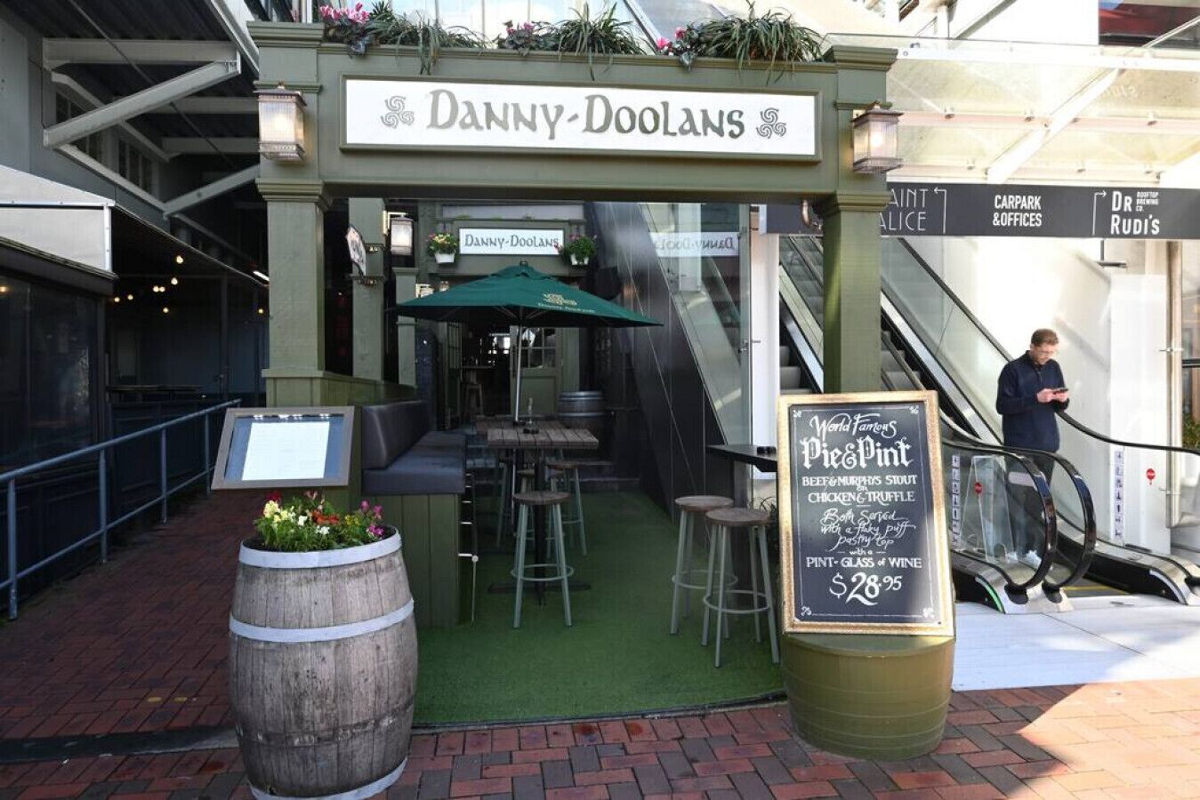 A restaurant named Danny-Doolans with outdoor seating and a menu board advertising pies and pint-glasses.