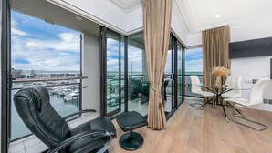 Ein modernes Zimmer mit Balkon, einem Glastisch mit Stühlen und Blick auf den Yachthafen.