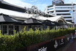 A restaurant named White Wongs with outdoor umbrellas and a hedge in front. - Sophisticated Spacious APT w/Stunning Harbour View (Auckland)