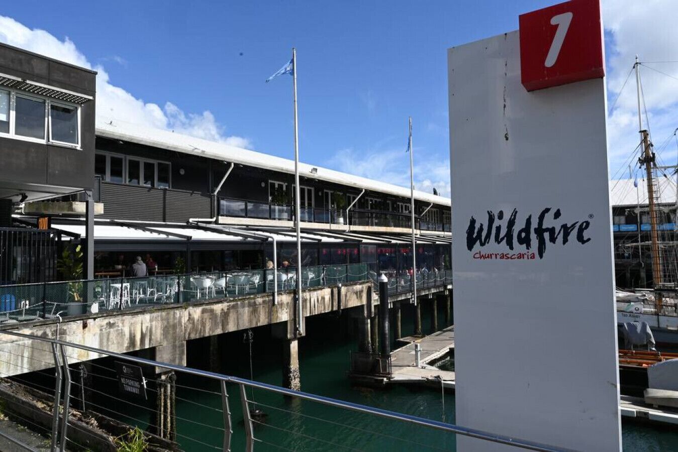 A waterfront restaurant named Wildfire Churrascaria with a view of the water and a bridge in the background.