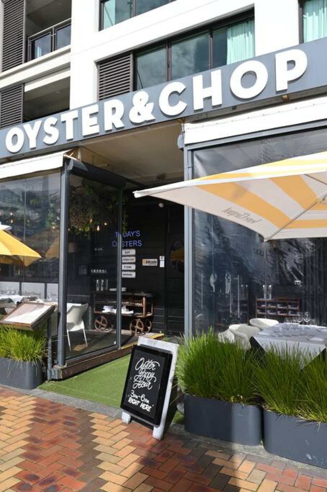 Exterior d'un restaurant anomenat Oyster & Chop, amb terrassa i una pissarra anunciant les especialitats.