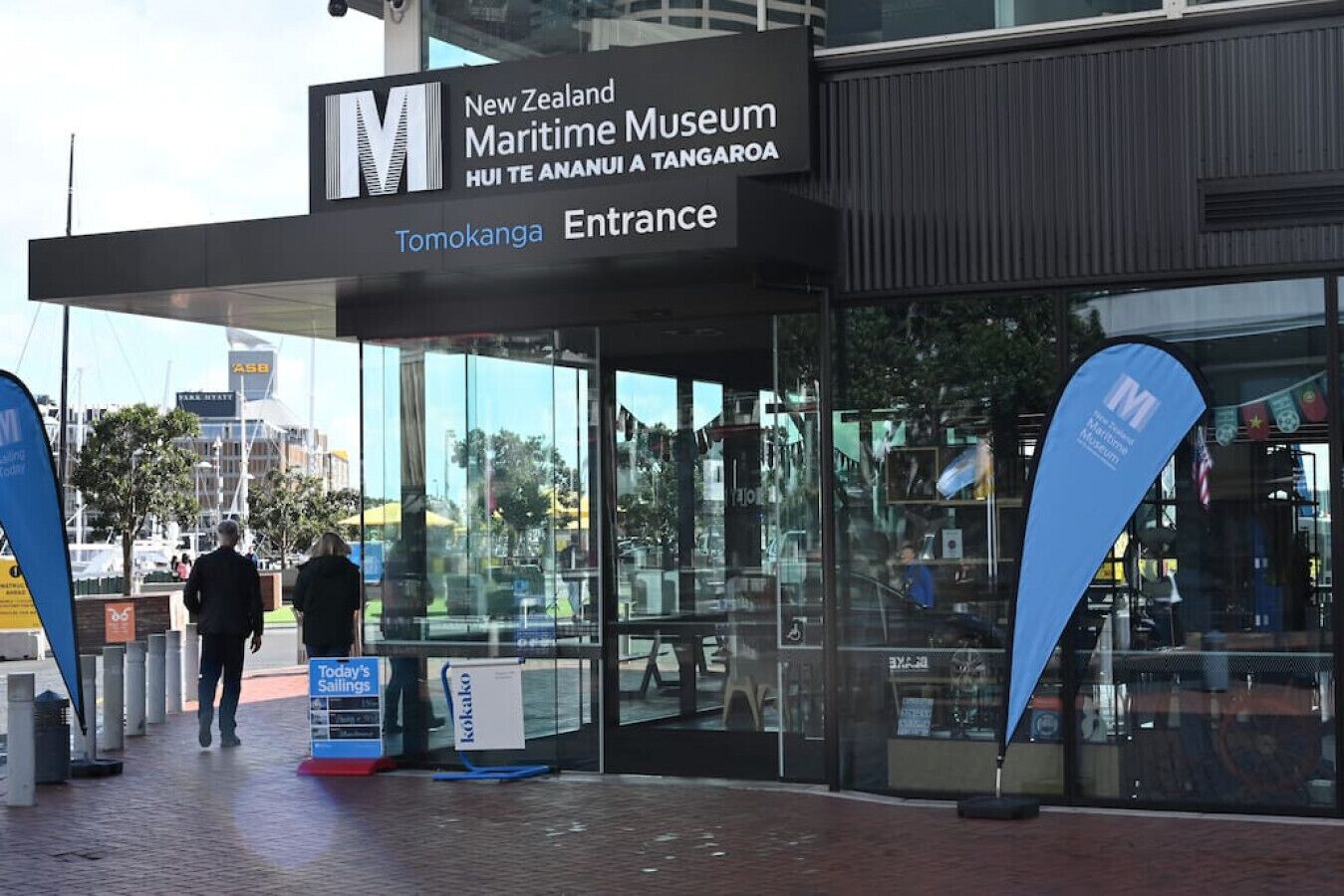 The entrance to the New Zealand Maritime Museum, featuring a modern glass facade and signage in both English and Māori.