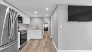 Une cuisine moderne équipée d’appareils électroménagers en acier inoxydable, d’un téléviseur à écran plat et d’un plancher en bois.