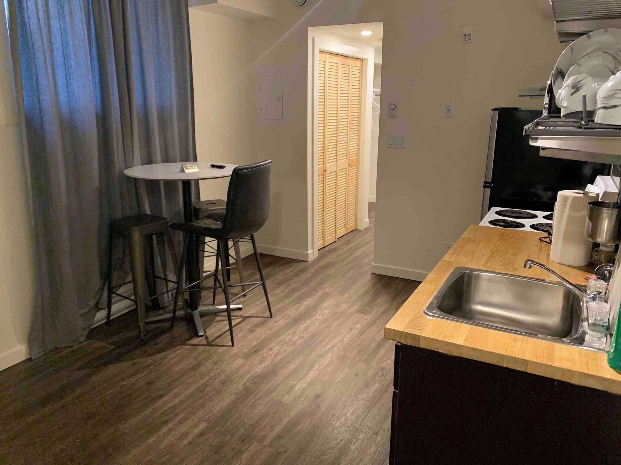 A compact kitchen with a sink, stove, and a dining area with chairs and a table.