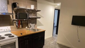 Eine moderne Küche mit Herd, Spüle und einem an der Wand montierten Fernseher.
