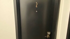 Eine schwarze Tür mit einem Zahlenschloss, ein kleiner Punkt an der Tür und die Zahl 2 an der linken Wand.