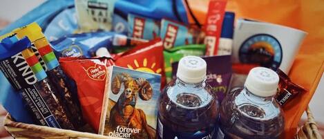 Una cesta con distintos artículos, como una barra de chocolate, un libro y dos botellas de Aquafina.