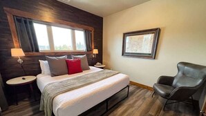 A bedroom with a bed, bedside tables, a chair, a window, and a framed map on the wall. - New! Beautiful Condo, Downtown Columbia Falls! (Columbia Falls)