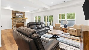 A spacious living room with a leather sofa, a coffee table, and a fireplace. - Chill in Style: Luxe Lodge w/ Hot Tub & Rooftop Lounge! (Branson)