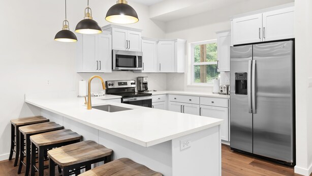 A modern kitchen with white cabinetry, stainless steel appliances, and wooden stools. - Chill in Style: Luxe Lodge w/ Hot Tub & Rooftop Lounge! (Branson)