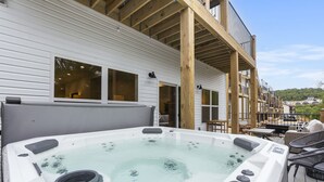 A hot tub on an outdoor deck with a wooden pergola and a view of a residential area. - Chill in Style: Luxe Lodge w/ Hot Tub & Rooftop Lounge! (Branson)