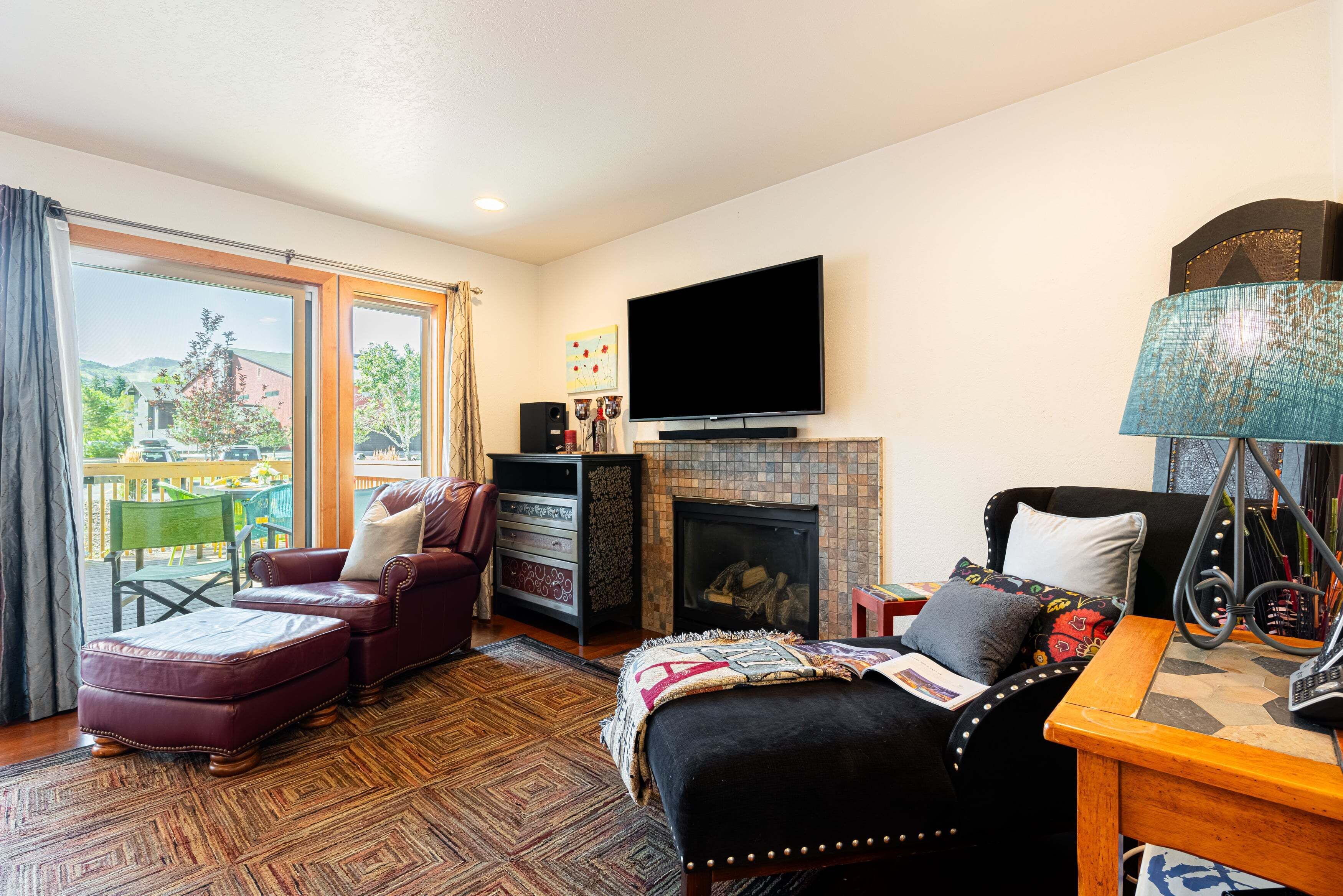 A living room with a fireplace, a television, and a view of the outdoors.