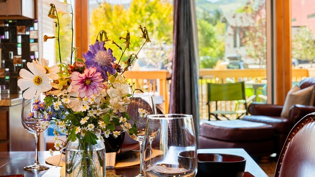 Une table à manger agrémentée d’un centre de table floral, de verres à vin et d’un chandelier.