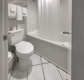 A bathroom with a toilet, a bathtub, and a shower curtain.