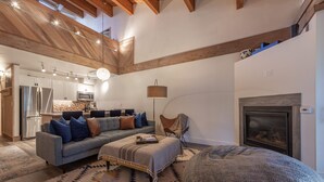 Un amplio salón con sofá, reposapiés y chimenea.